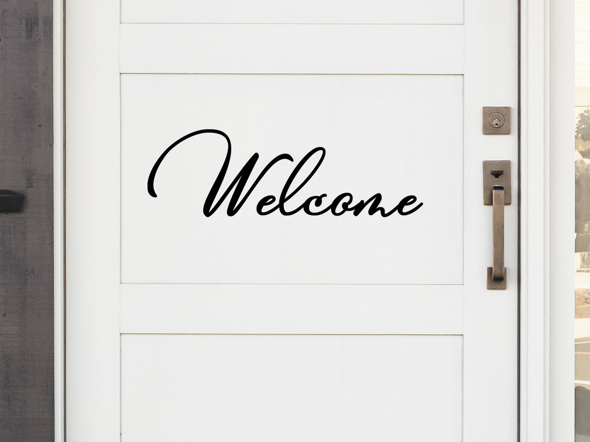 Front door decal that says, ‘Welcome’ in a cursive font  on a front porch door. 