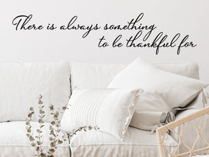 Living room wall decals that say ‘There Is Always Something To Be Thankful For’ in a cursive font on a living room wall. 