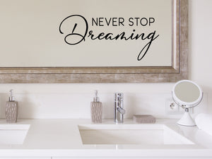 Wall decals for bathroom that say ‘Never Stop Dreaming’ in a script font on a bathroom mirror.
