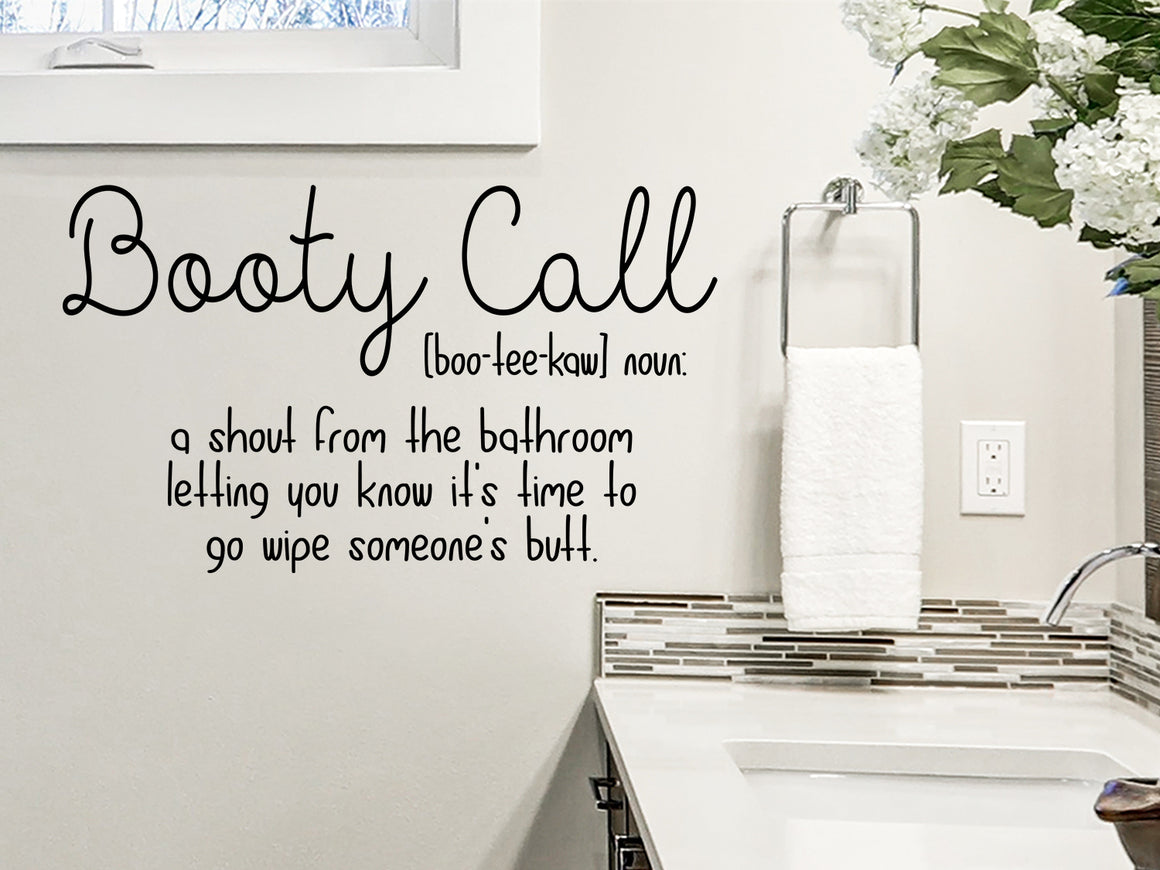 Wall decal for bathroom that says ‘booty call: a shout from the bathroom letting you know it's time to go wipe someone's butt’ on a bathroom wall.