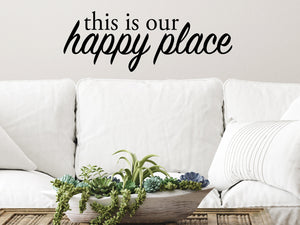 Living room wall decals that say ‘This Is Our Happy Place’ in a script font on a living room wall. 