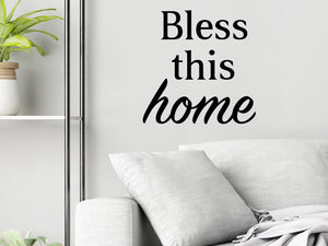 Living room wall decals that say ‘Bless This Home’ in a bold font on a living room wall. 