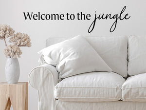 Living room wall decals that say ‘Welcome To The Jungle’ in a script font on a living room wall. 
