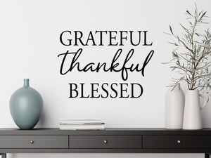 Living room wall decals that say ‘Grateful Thankful Blessed’ in a script font on a living room wall. 
