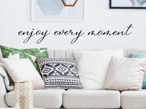 Living room wall decals that say ‘enjoy every moment’ on a living room wall. 