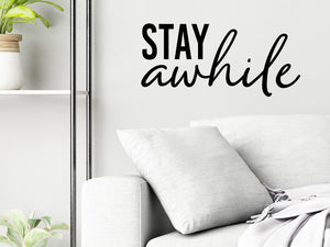 Living room wall decals that say ‘Stay Awhile’ in a bold font on a living room wall. 