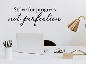 Wall decal for the office that says ‘Strive For Progress Not Perfection’ in a script font on an office wall.