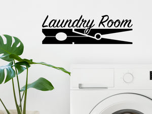 Laundry room wall decal that says ‘Laundry Room (ClothesPin)’ in a script font on a laundry room wall.