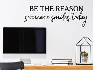 Wall decal for the office that says ‘Be The Reason Someone Smiles Today’ in a script font on an office wall.