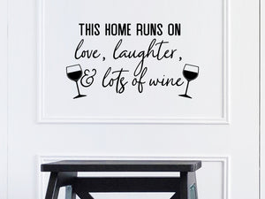 Wall decals for kitchen that say ‘This House Runs On Love Laughter And Lots Of Wine’ with wine glass designs on a kitchen wall.