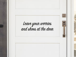 Front door decal that says, ‘Leave Your Worries And Shoes At The Door' in a cursive font on a front porch door. 