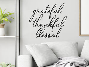 Living room wall decals that say ‘Grateful Thankful Blessed’ in a cursive font on a living room wall. 
