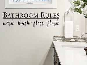 Wall decal for bathroom that says ‘Bathroom Rules. Wash, brush, floss, flush'’ on a bathroom wall.