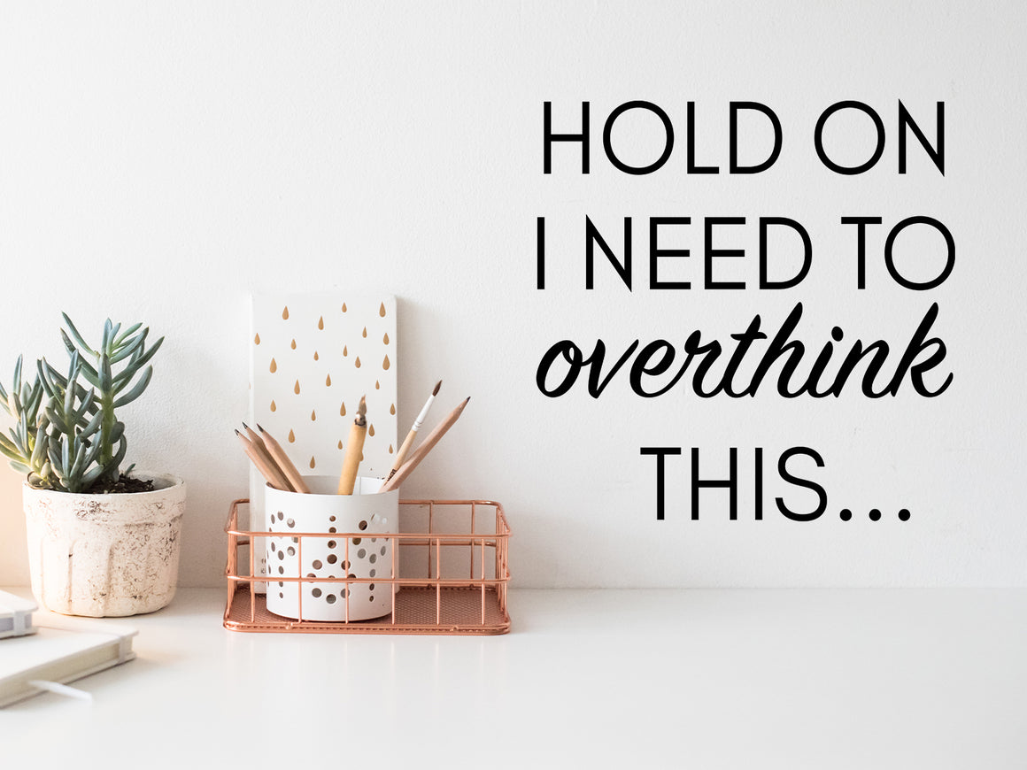 Wall decal for the office that says ‘Hold On I Need To Overthink This’ in a script font] on an office wall.