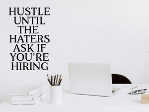 Wall decal for the office that says ‘Hustle Until The Haters Ask If You're Hiring’ in a print font on an office wall.