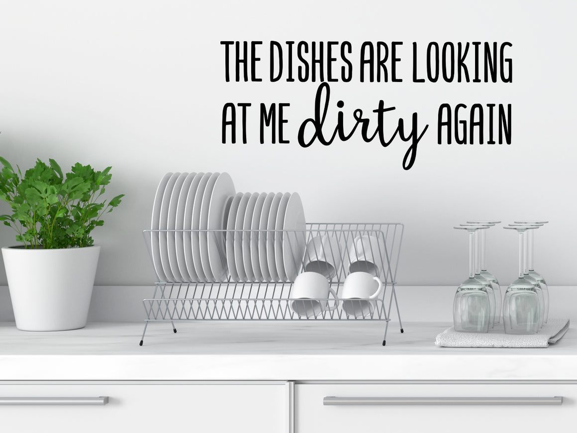 Wall decals for kitchen that say ‘The Dishes Are Looking At Me Dirty Again’ in a script font on a kitchen wall.