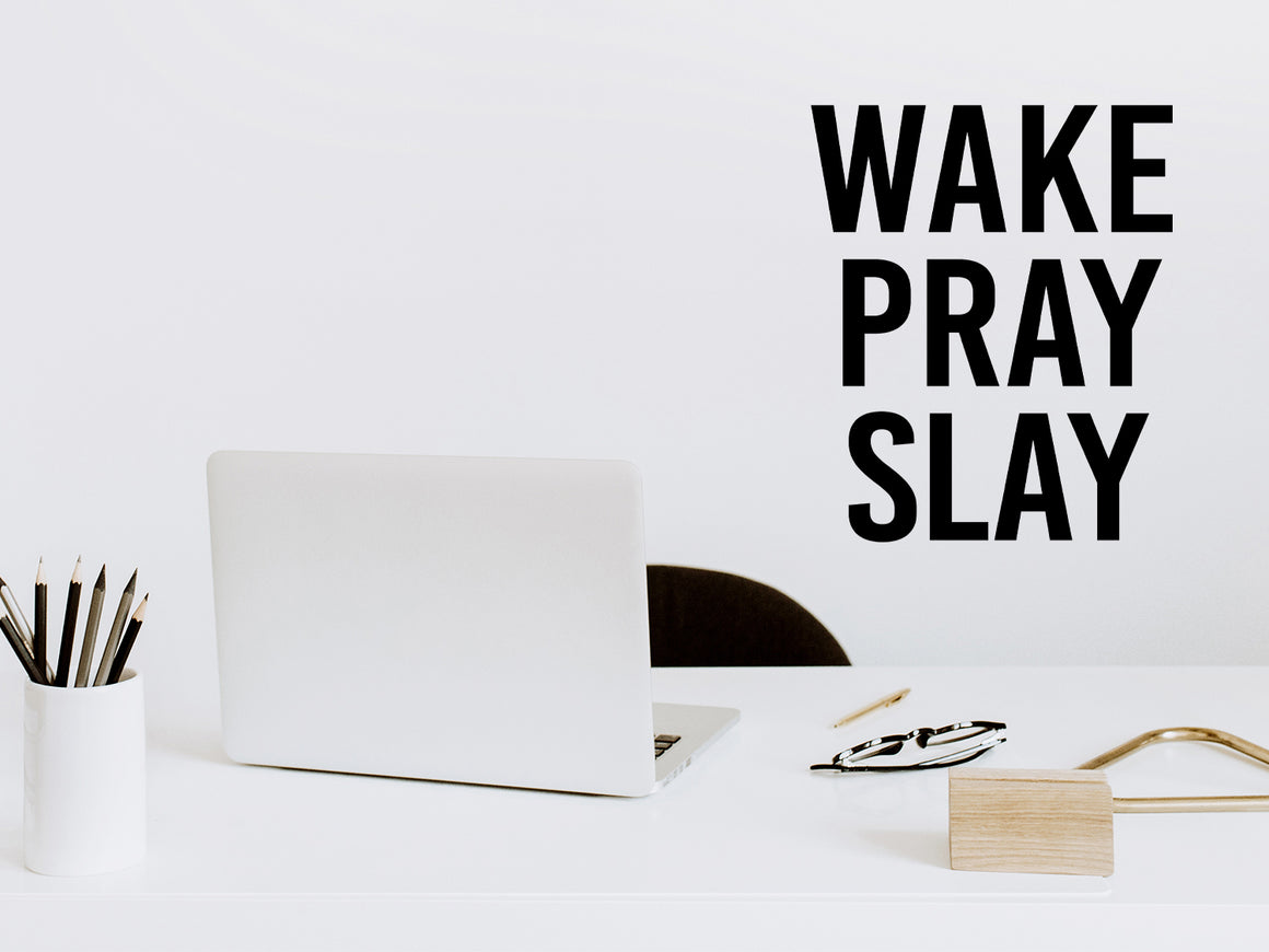 Wall decal for the office that says ‘Wake Pray Slay’ in a print font on an office wall.