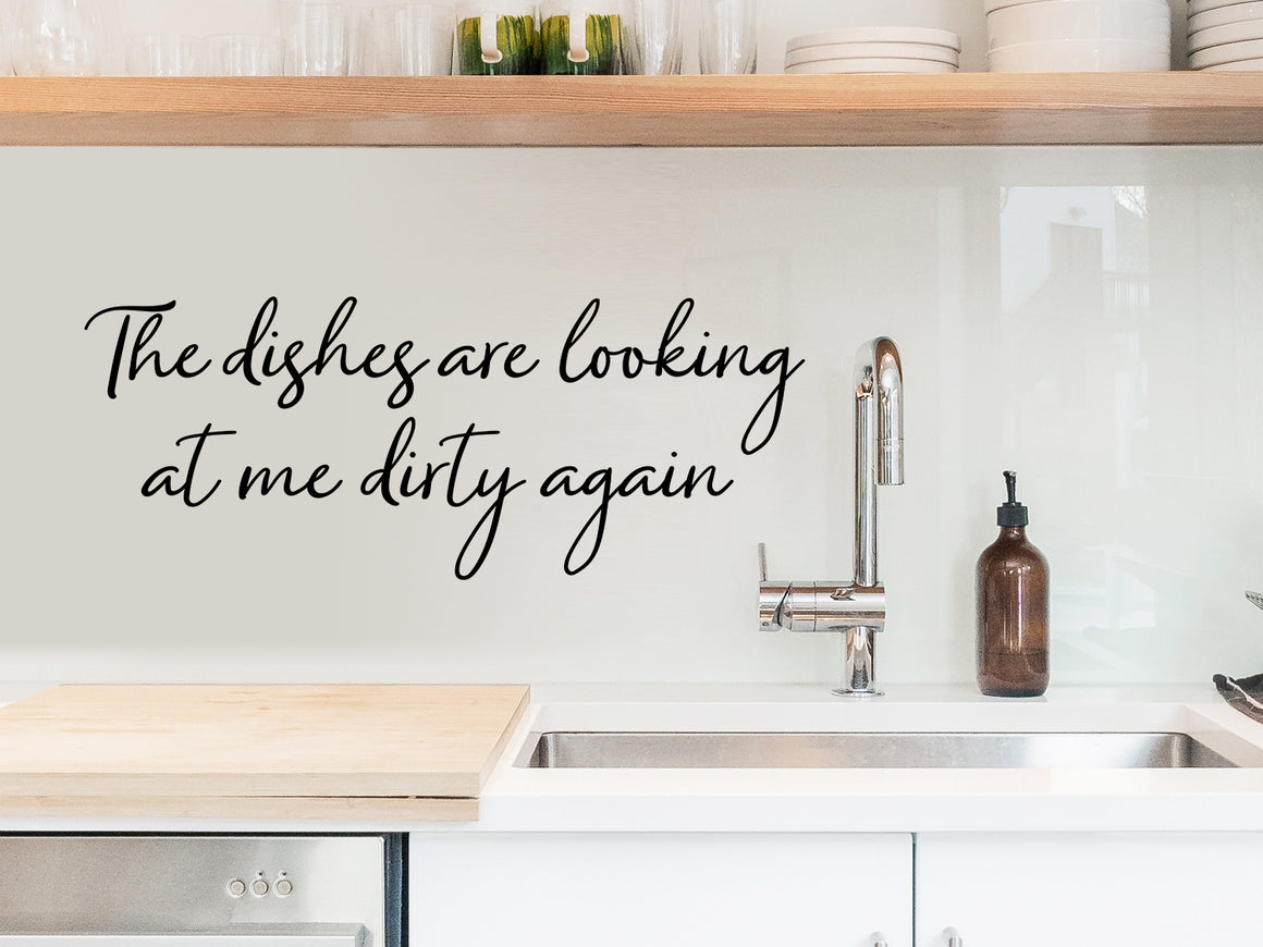 Wall decals for kitchen that say ‘The Dishes Are Looking At Me Dirty Again’ in a cursive font on a kitchen wall.