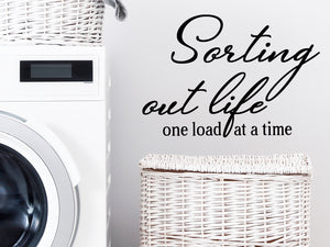 Laundry room wall decal that says ‘Sorting Out Life One Load At A Time’ in a script font on a laundry room wall.