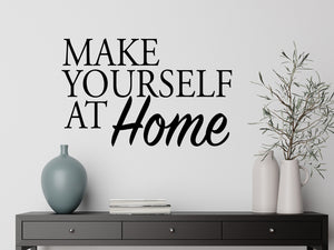 Living room wall decals that say ‘Make Yourself At Home’ in a bold font on a living room wall. 
