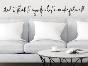 Living room wall decals that say ‘And I think to myself what a wonderful world’ in a cursive font on a living room wall. 
