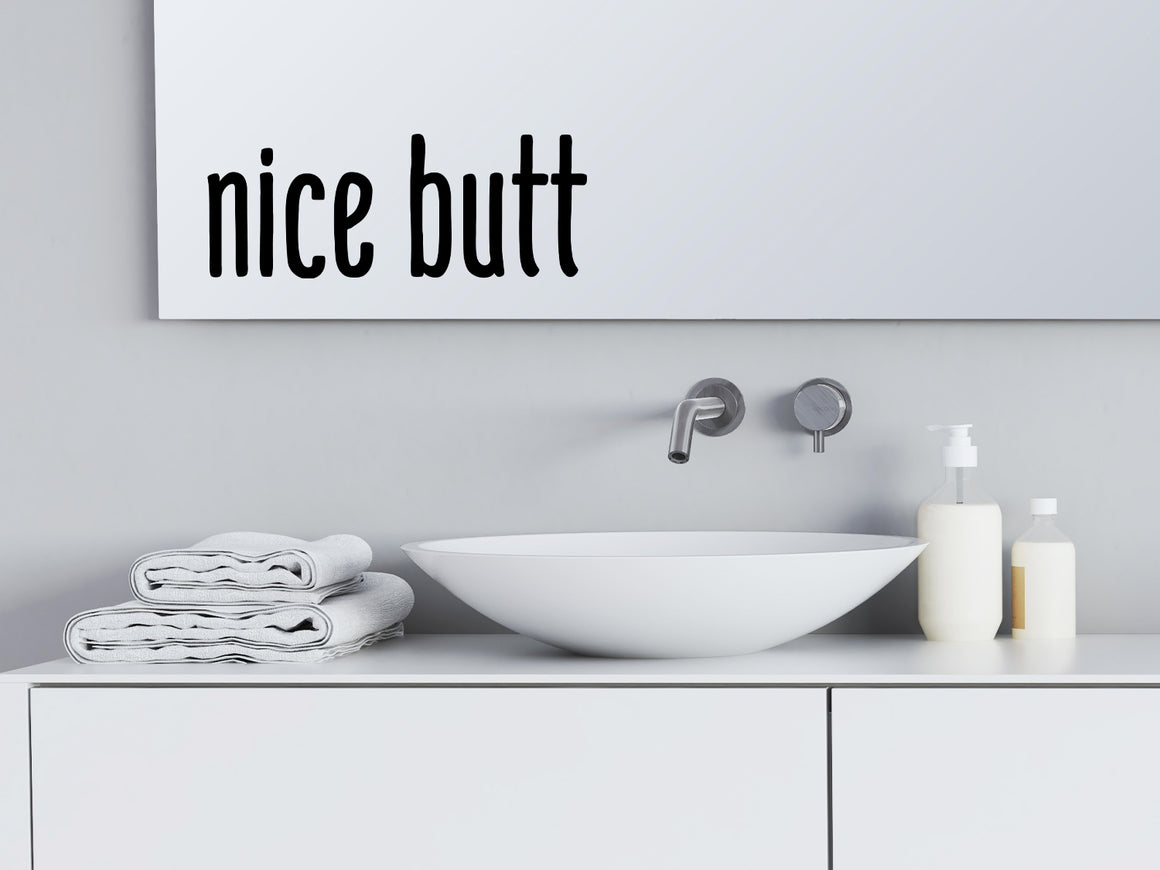 Wall decals for bathroom that say ‘Nice Butt’ in a print font on a bathroom mirror.