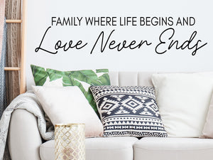 Living room wall decals that say ‘Family where life begins and love never ends’ in a script font on a living room wall. 