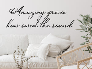 Living room wall decals that say ‘Amazing Grace How Sweet The Sound’ in a cursive font on a living room wall. 