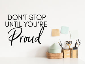 Wall decal for the office that says ‘Don't Stop Until You're Proud’ in a script font on an office wall.