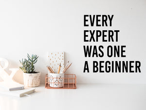 Wall decal for the office that says ‘Every Expert Was Once A Beginner’ in a bold font on an office wall.