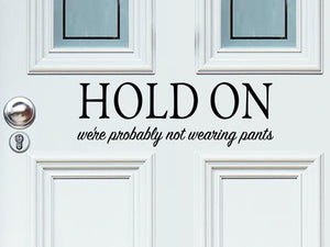 Front door decal that says, ‘Hold On We're Probably Not Wearing Pants’ on a front porch door. 