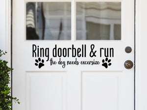 Front door decal that says, ‘Ring door bell & run the dog needs exercise’ on a front porch door. 