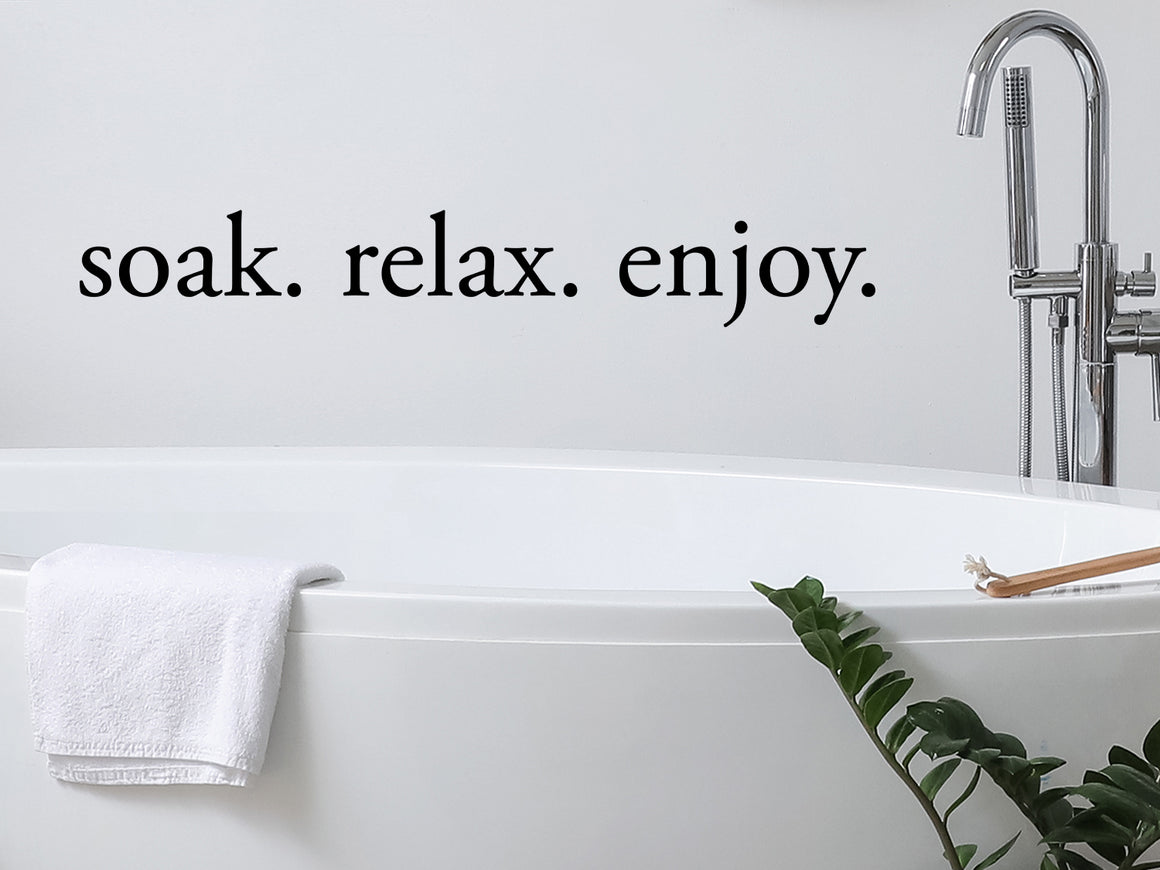 Wall decals for bathroom that say ‘Soak Relax Enjoy’ in a print font on a bathroom wall.