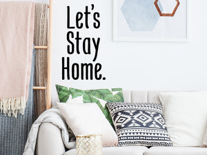 Living room wall decals that say ‘Let's stay home’ in print on a living room wall. 