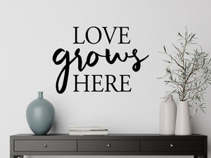 Living room wall decals that say ‘Love Grows Here’ in a bold font on a living room wall. 