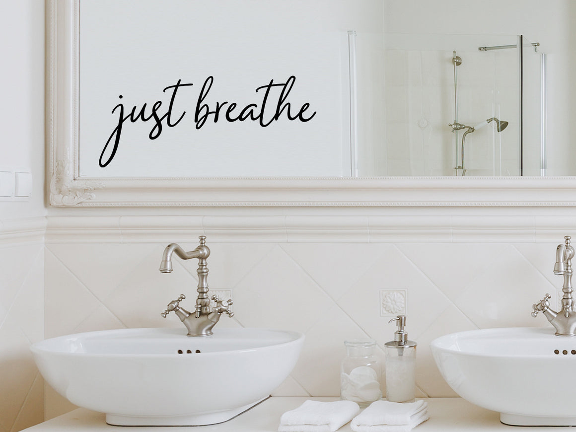 Wall decals for bathroom that say ‘Just Breathe’ in a cursive font on a bathroom mirror.