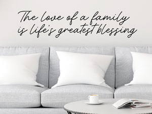 Living room wall decals that say ‘The love of a family is life's greatest blessing’ in a script font on a living room wall. 