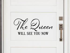 Front door decal that says, ‘The Queen Will See You Now Cursive’ on a front porch door. 