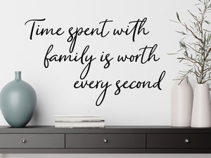Living room wall decals that say ‘Time Spent With Family Is Worth Every Second’ in a script font on a living room wall. 
