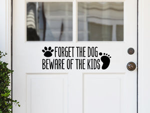 Front door decal that says, ‘Forget The Dog Beware Of The Kids’ on a front porch door. 