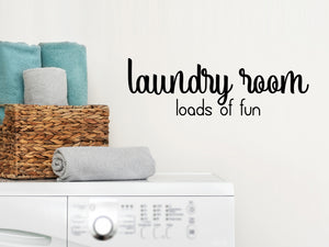Laundry room wall decal that says ‘Laundry Room Loads Of Fun’ in a script font on a laundry room wall