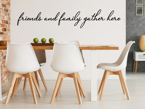 Wall decals for kitchen that say ‘Friends And Family Gather Here’ in a cursive font on a kitchen wall.