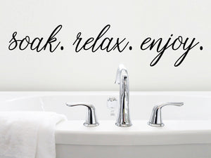 Wall decals for bathroom that say ‘soak. relax. enjoy.’ on a bathroom wall.
