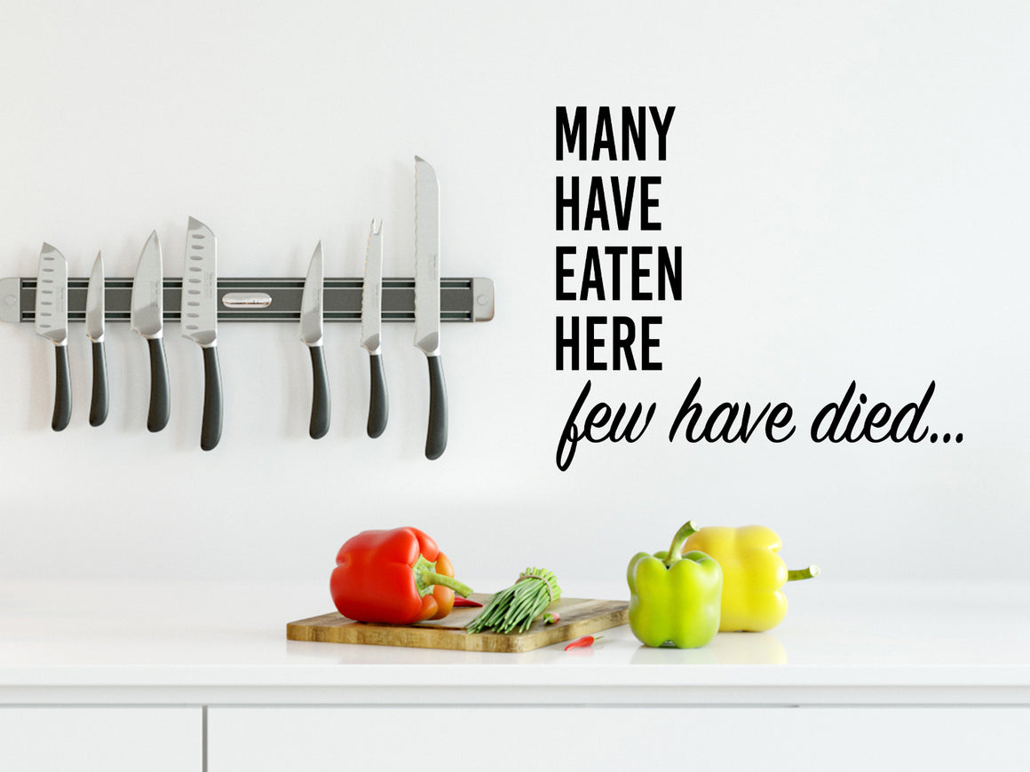 Wall decals for kitchen that say ‘Many Have Eaten Here Few Have Died’ in a bold font on a kitchen wall.