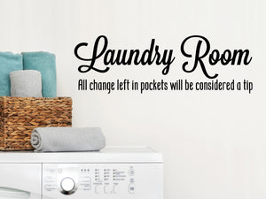 Laundry room wall decal that says ‘Laundry Room All Change Left In Pockets Will Be Considered A Tip’ in cursive on a laundry room wall.