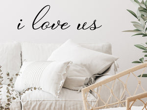 Living room wall decals that say ‘I Love Us’ in a cursive font on a living room wall. 