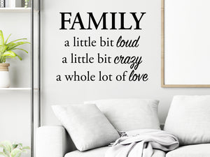 Living room wall decals that say ‘Family A Little Bit Loud A Little Bit Crazy & A Whole Lot Of Love’ in a script font on a living room wall.