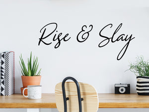 Wall decal for the office that says ‘Rise And Slay’ in a cursive font on an office wall.