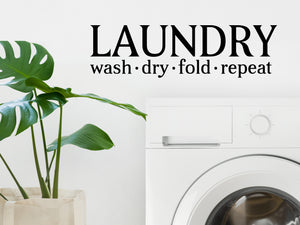 Laundry room wall decal that says ‘Laundry Wash Dry Fold Repeat’ on a laundry room wall.