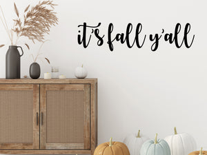 Living room wall decals that say ‘It's Fall Y'all’ in a cursive font on a living room wall. 